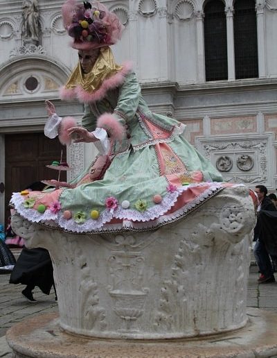 photo - carnaval de venise - zoom souvenirs - femme - robe - masque - chapeau - vert - rose - macaron - dentelle - puit - marbre - sculpture