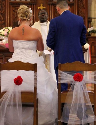 photo - mariage - zoom souvenirs - couple - église - prêtre - chaise - nœud - costume - robe - marron - blanc - bleu - rouge - fleur