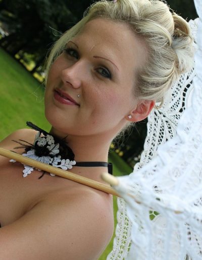 photo - mariage - zoom souvenirs - femme - ombrelle - sourire - collier - parc - arbre - pelouse - blanc - vert - noir - chignon