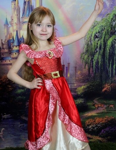photo - thématique - zoom souvenirs - fille costume - princesse - décor - château - pelouse - vert - rouge - enfant - sourire