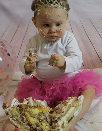 photo - smash the cake - zoom souvenirs - bébé - gâteau - anniversaire - tutu - maillot - salir - écrasé - couronne - ballon - main - rose - blanc