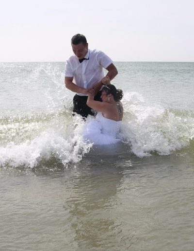 photo - trash the dress - zoom souvenirs - couple - mariage - mer - vague - robe - chemise - bijoux - blanc - noir - chignon - costume