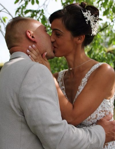 photo - mariage - zoom souvenirs - couple - baiser - parc - arbre - vert - gris - chignon - dentelle - blanc - collier